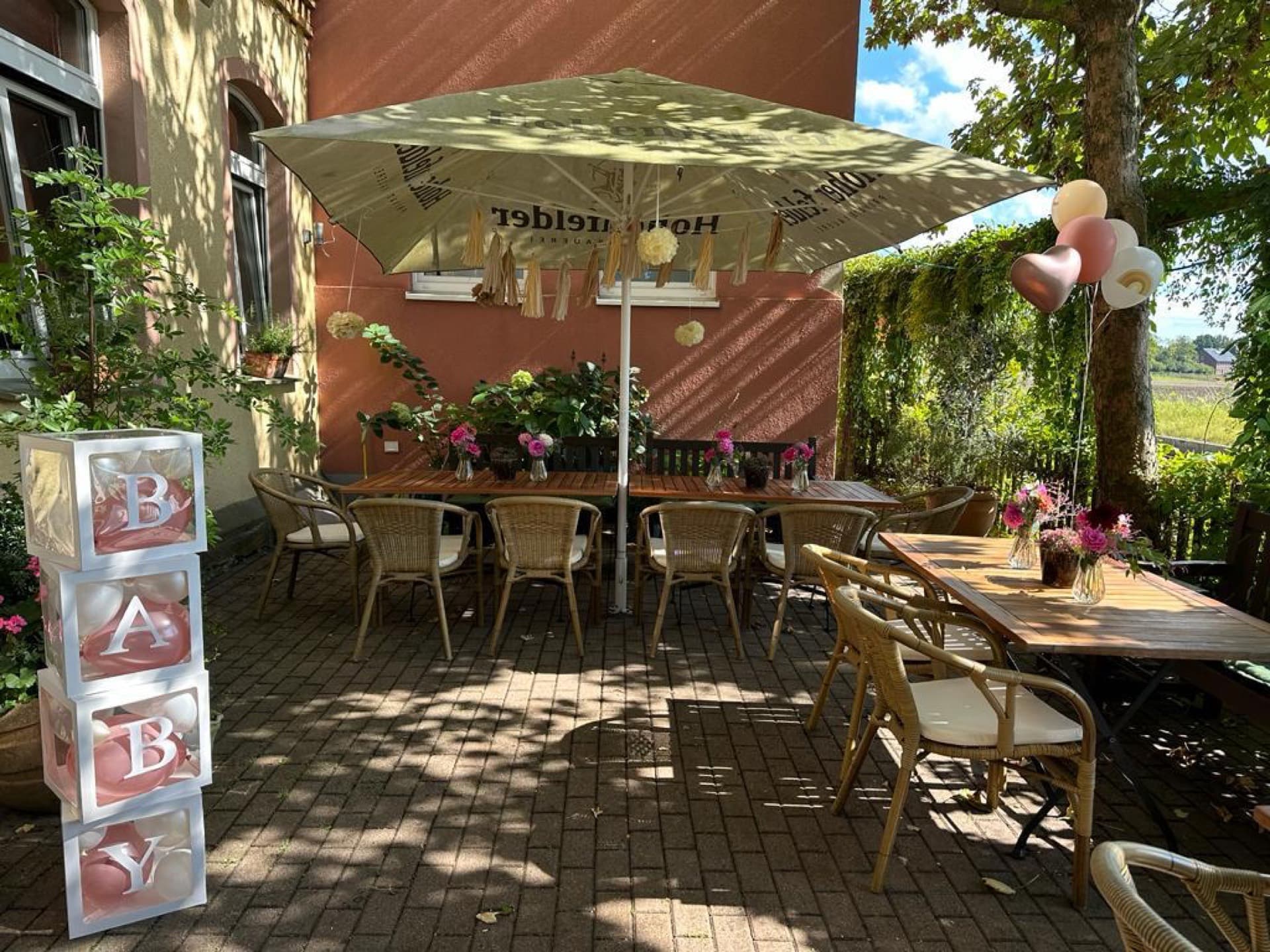 Sonniger Biergarten mit festlicher Dekoration für eine Feier